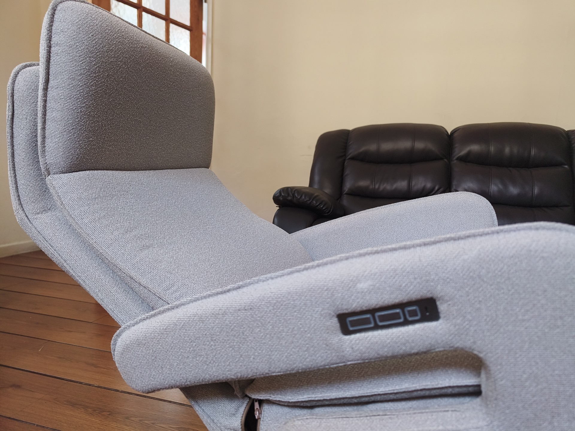 Close-up side view of the reclined chair showing the backlit touch panel built into the armrest.