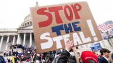 A man holds a "stop the steal" sign as rioters take over the steps of the Capitol on Jan. 6, 2021