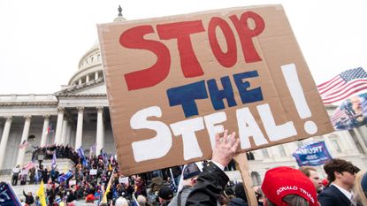 A man holds a &quot;stop the steal&quot; sign as rioters take over the steps of the Capitol on Jan. 6, 2021