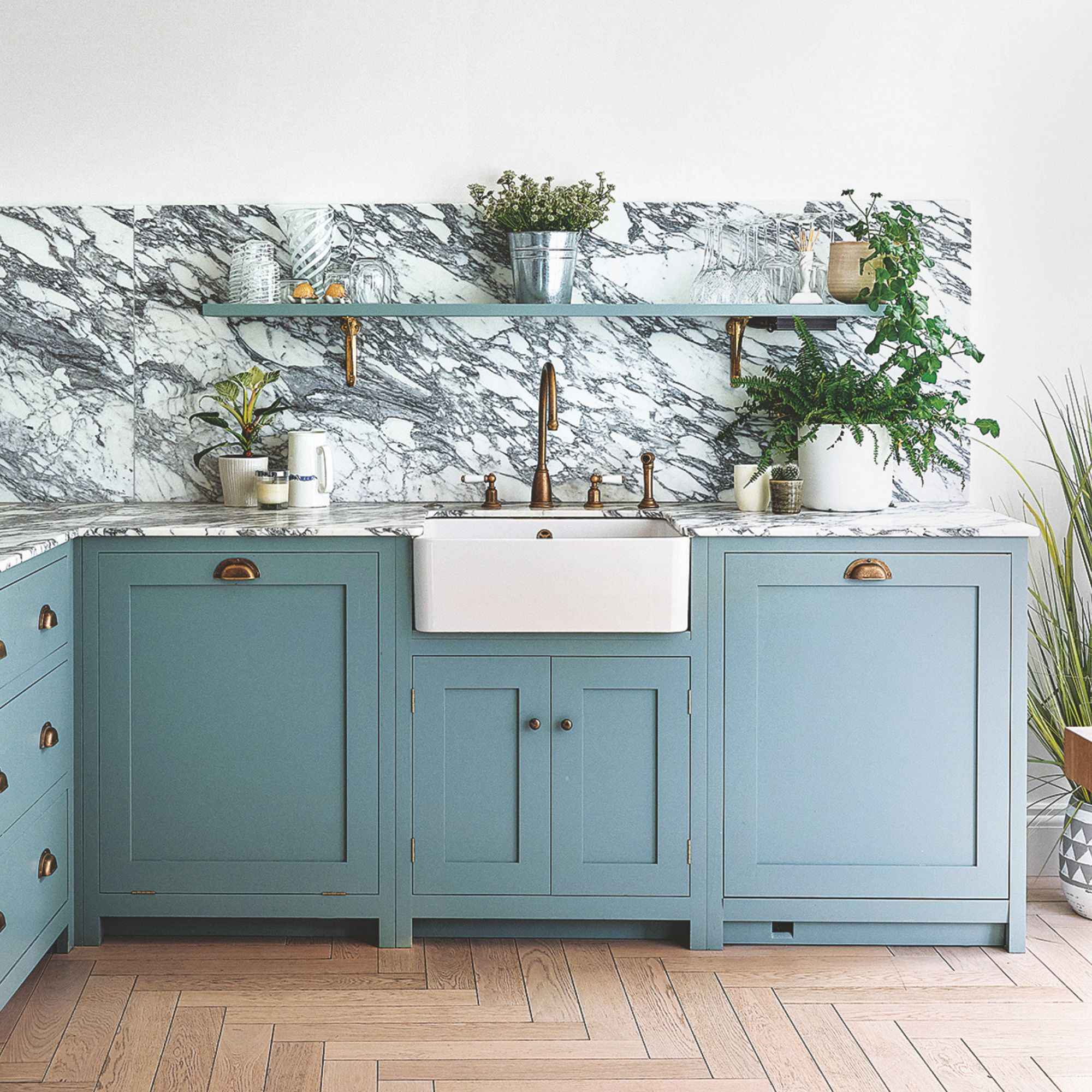 White painted kitchen with blue painted cabinets and marble worktop and splashback