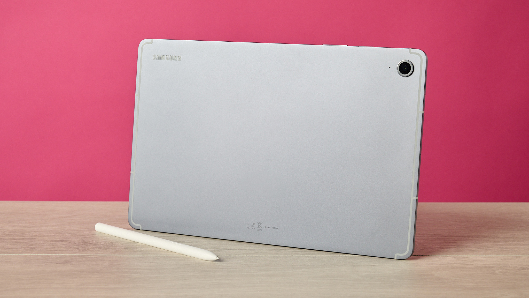 The back of the Samsung Galaxy Tab S10 FE behind the S Pen and in front of a pink background.