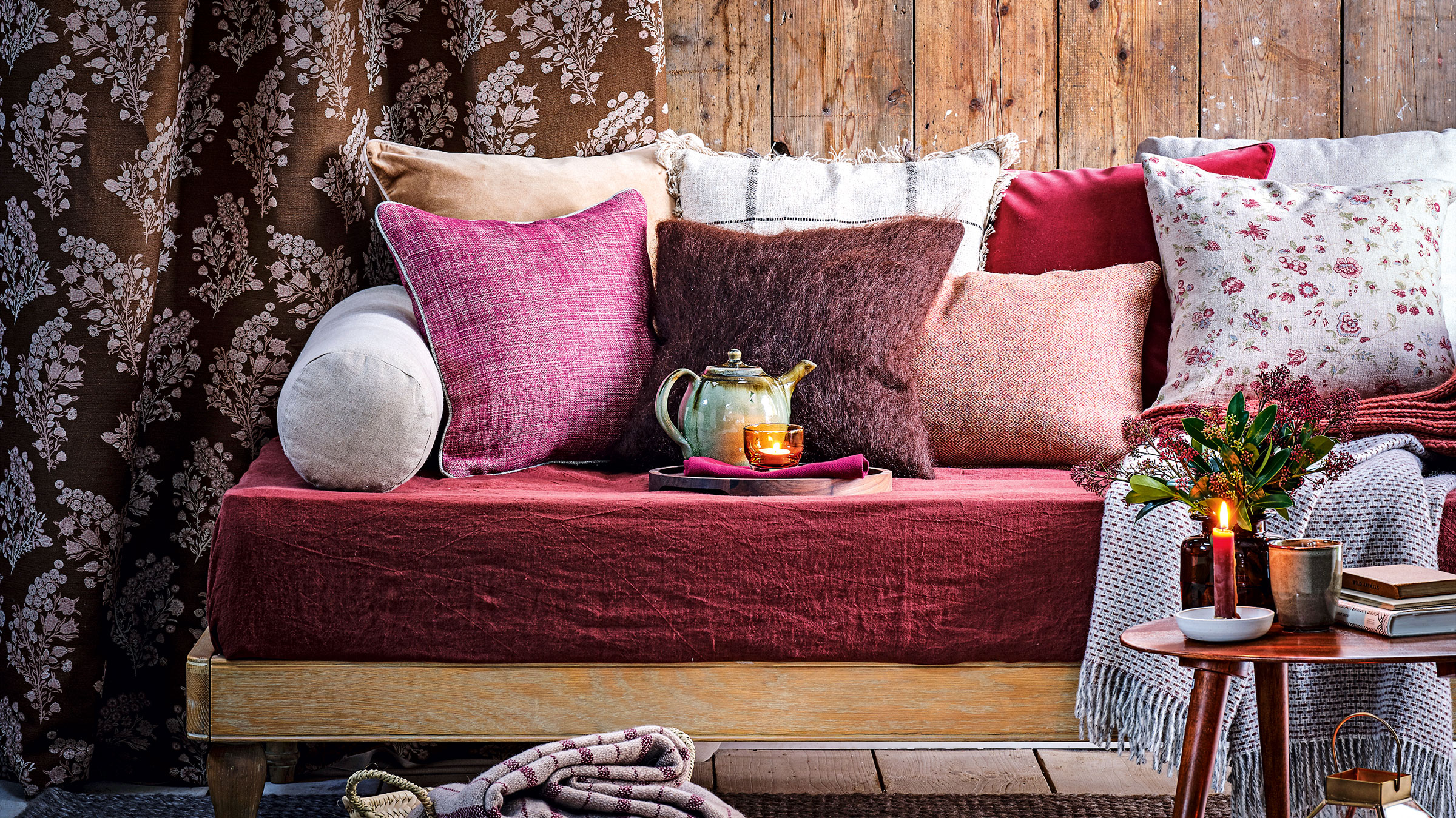 Purple cushions on a day bed with wooden wall panelling and grey carpet