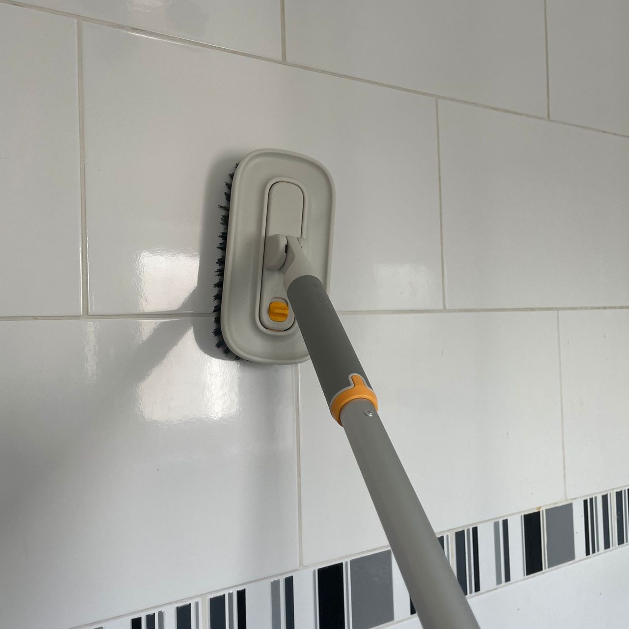 Using Joseph Joseph cleantech tile scrubber on white bathroom tiles