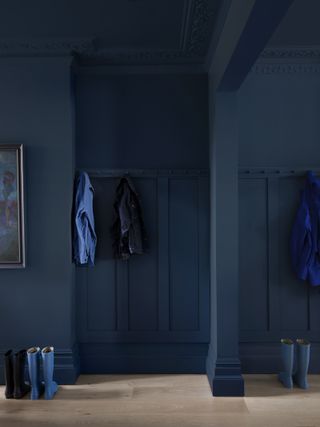 A boot room with ceilings and walls painted in a dark inky blue shade