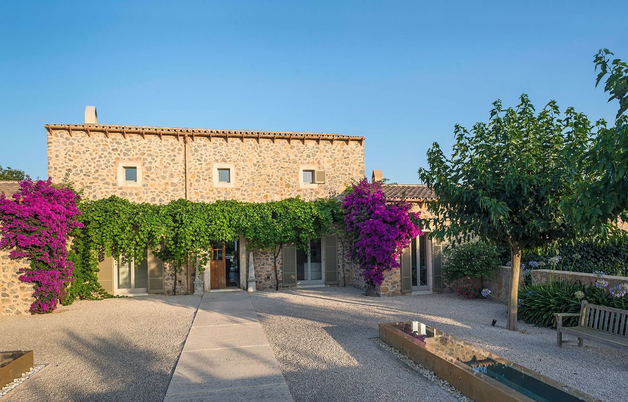 Exterior of Mallorcan home with water feature and bougainvillea on house blue sky