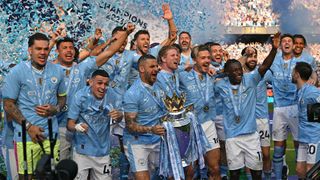 Kyle Walker holds the Premier League trophy in front of his Manchester City teammates after winning the 2023/24 league title