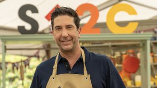 David Schwimmer in a dark top and pale apron in the tent for The Great Celebrity Bake Off for Stand Up to Cancer