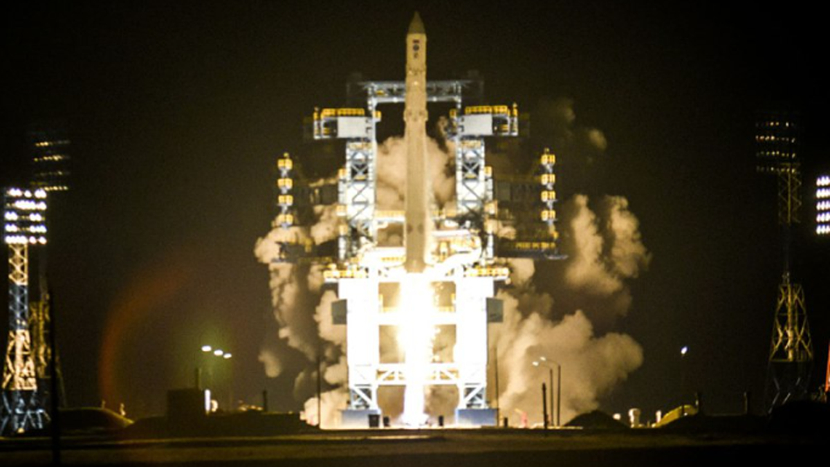 Russian Angara rocket launches at night surrounded by launch pad gantries