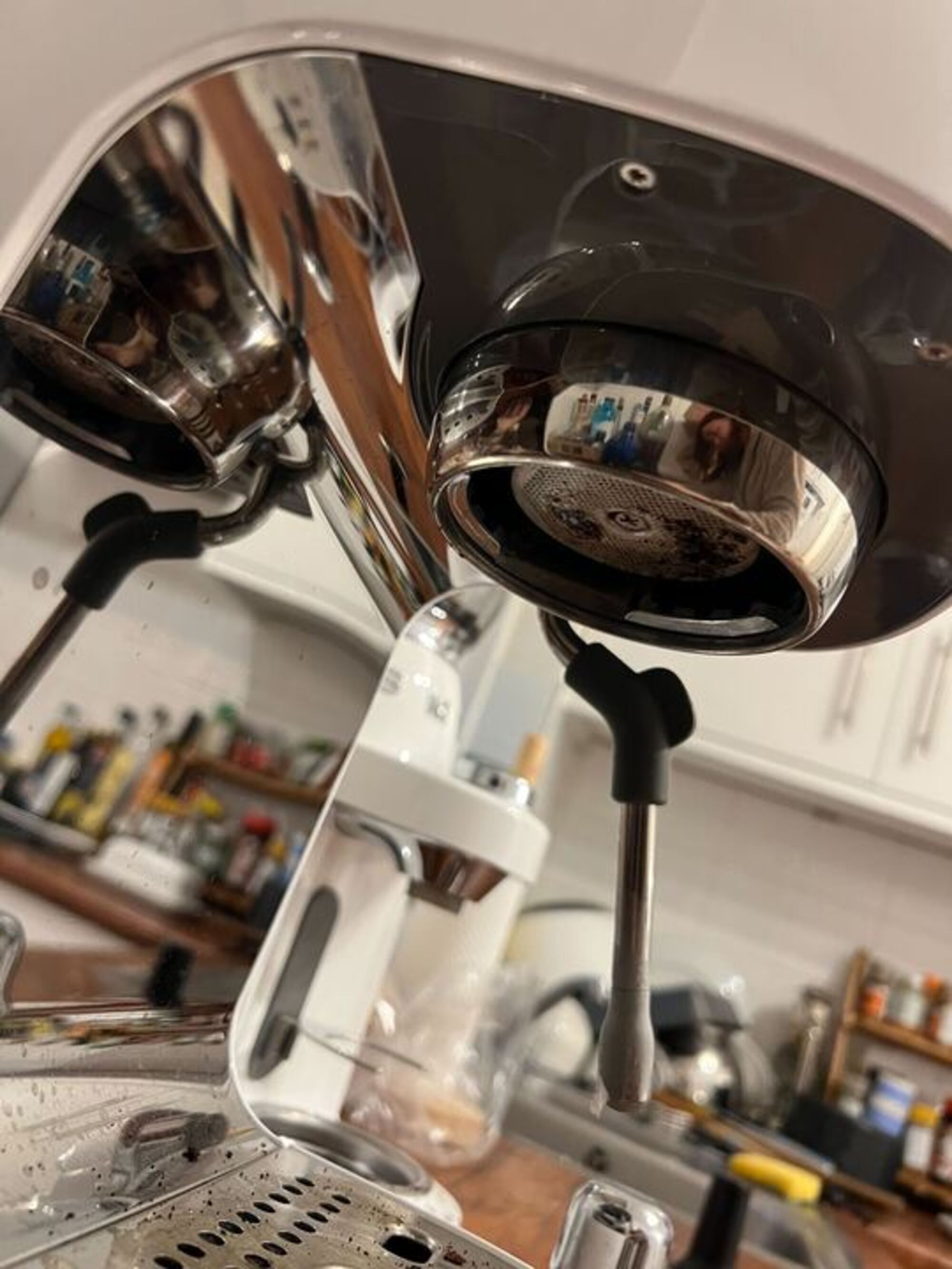 Image of the underside of an espresso machine showing a dirty grouphead.