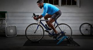 A man riding a road bike fitted to a Tacx Boost turbo trainer