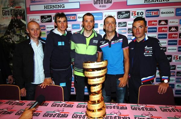 Riders gather around the Giro trophy