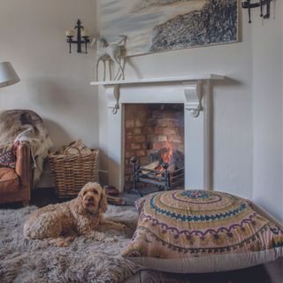 A living room corner with an open fire lit in a fireplace, leather armchair and sheepskin rug
