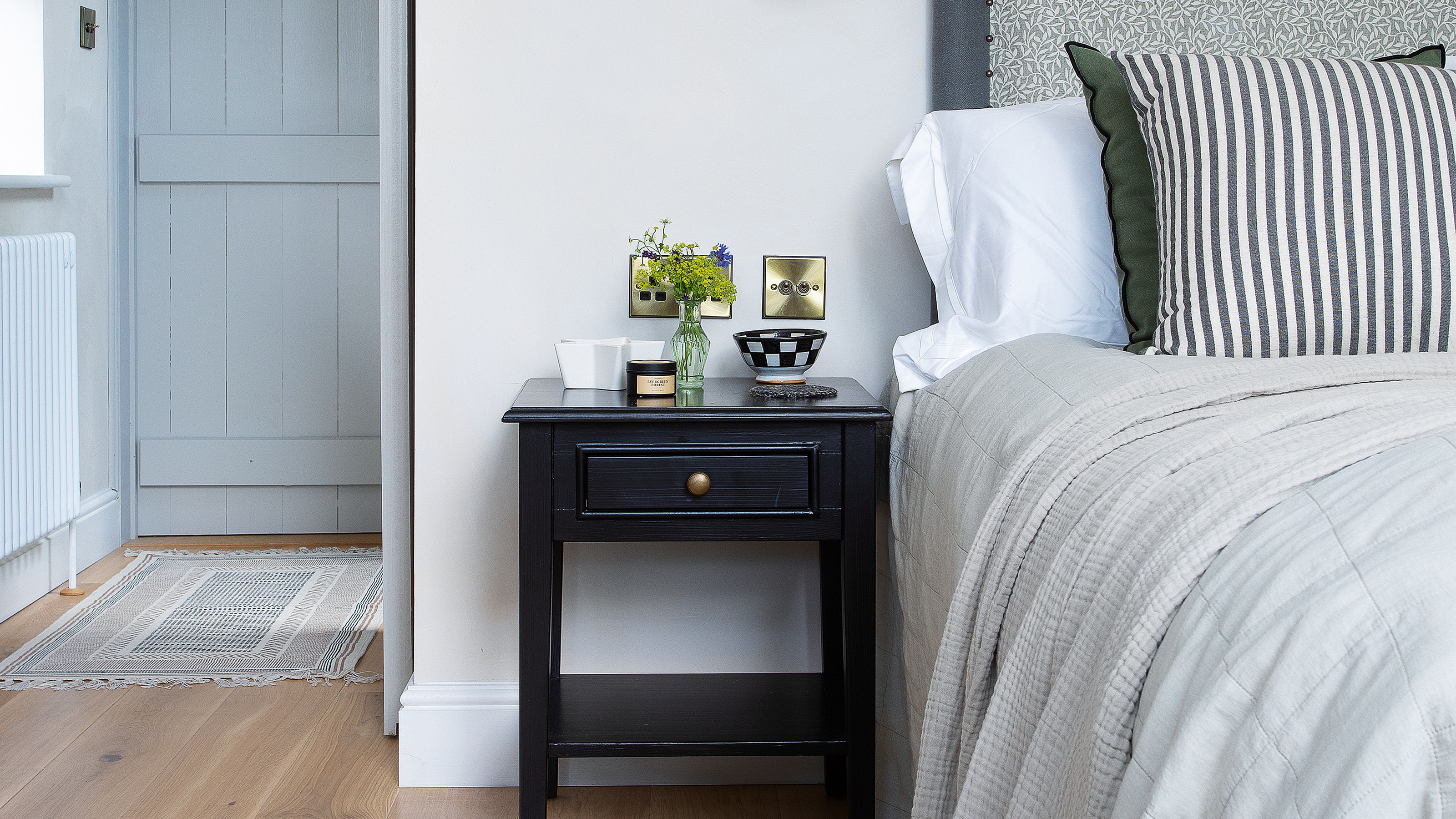A bedroom with an upholstered headboard and striped cushions on the bed