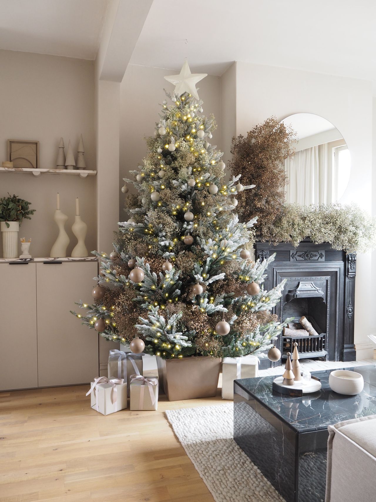 a living room decorated for christmas with a tree and fireplace covered in gypsophila