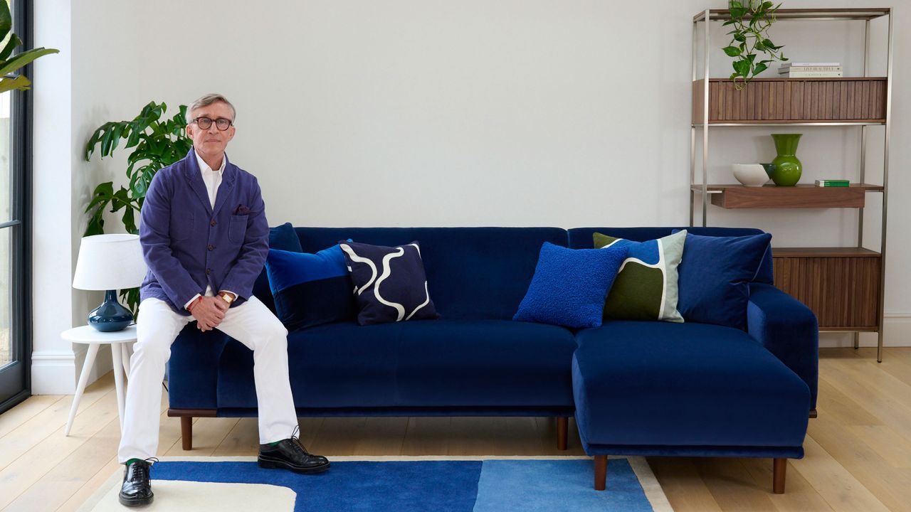 Jasper Conran sitting on edge of blue sofa