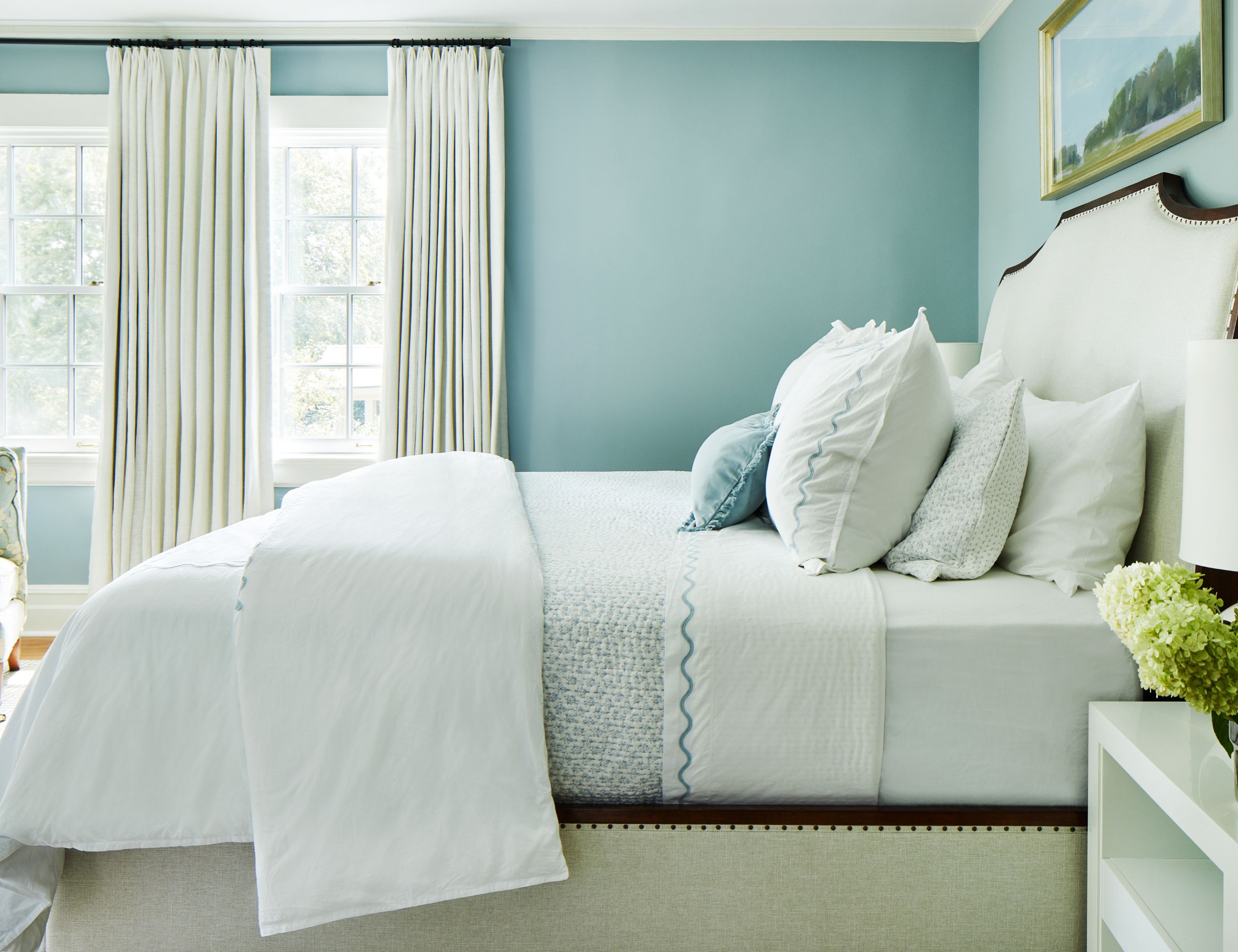 Soothing blue living room with white bedding and cream bedframe with headboard