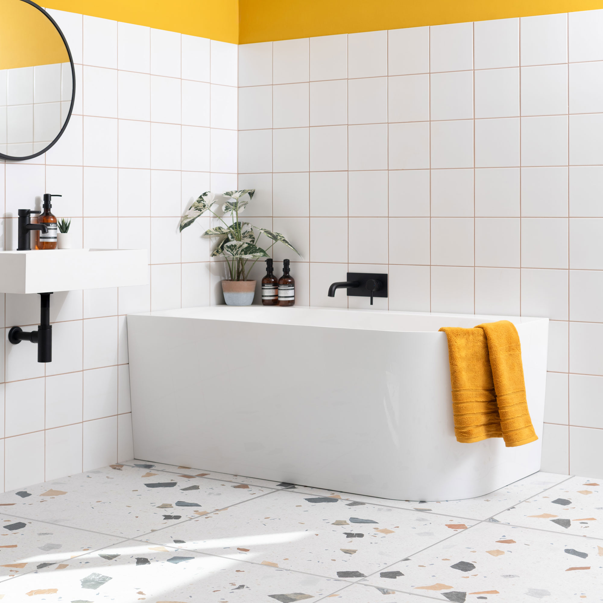 white bathroom with white wall tiles and terrazzo style floor tiles with yellow painted walls