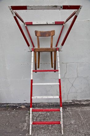 white concrete wall, concrete floor, red and white stripe ladder with wooden stool incorporated