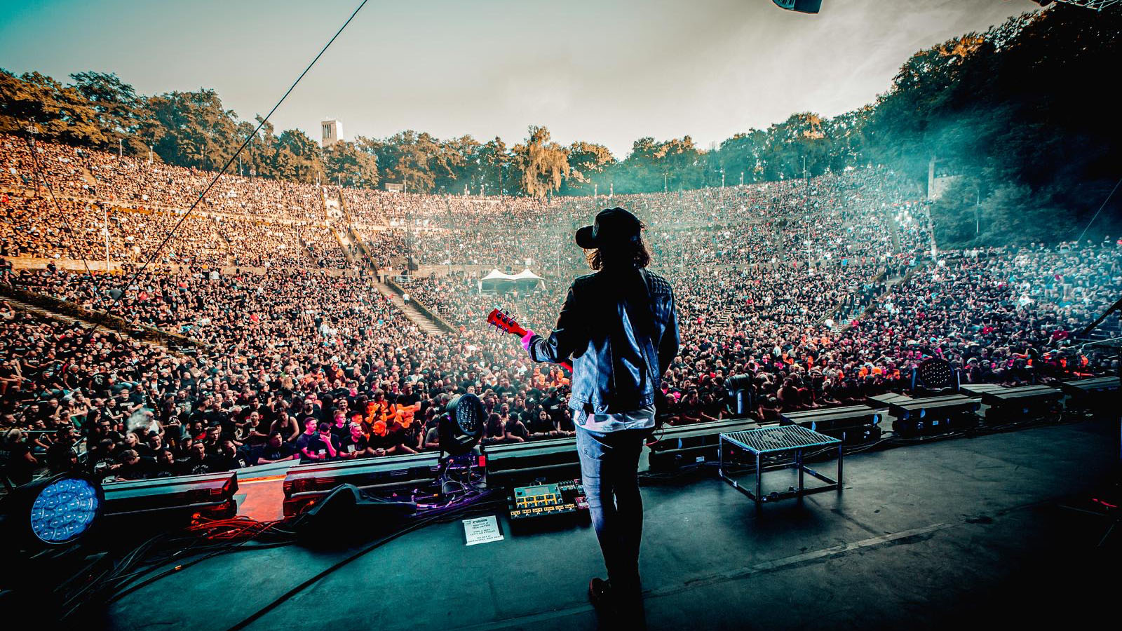 Ian "Shiner" Thomas of Those Damn Crows onstage playing to a festival crowd with his Gibson Les Paul. He wears a baseball cap and sunglasses.