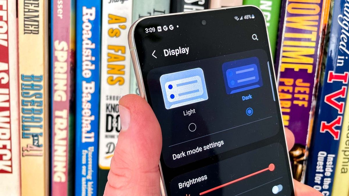 A person holding a Galaxy S23 and configuring dark mode
