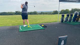 A golfer poses after hitting a shot with a golf iron