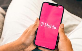 A woman holding an iPhone in her hands with the T-Mobile logo superimposed on the screen