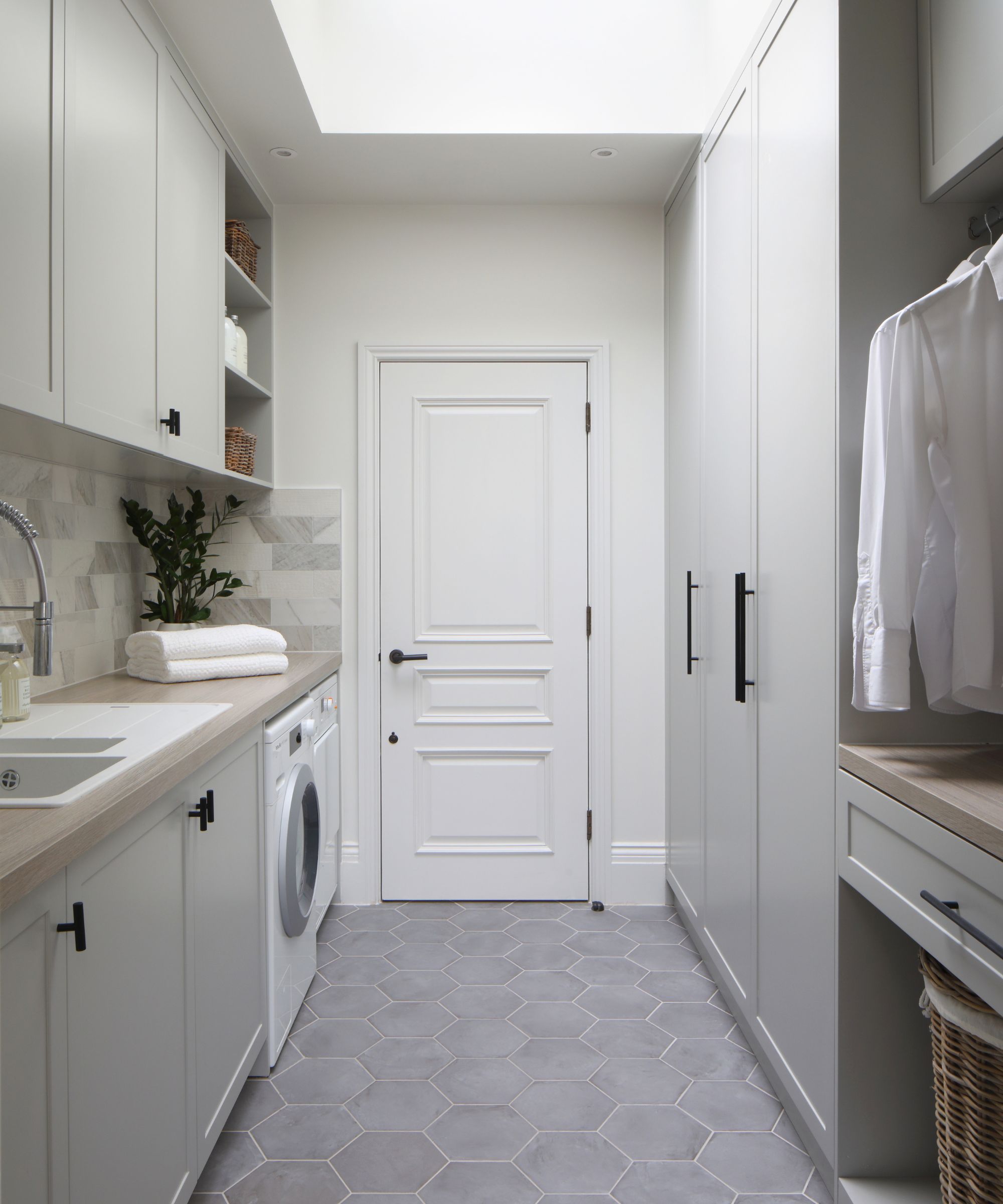 Light laundry room with a skylight and light cabinets and materials