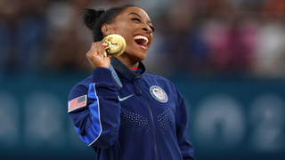 Simone Biles holds up gold medal at Olympics 2024.