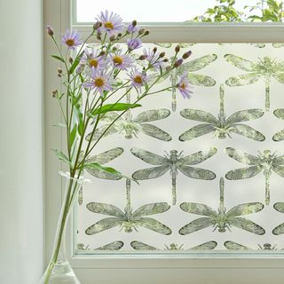 white bathroom window with dragon fly window film and flower vase
