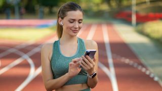 a female runner smiling as she looks at her phone