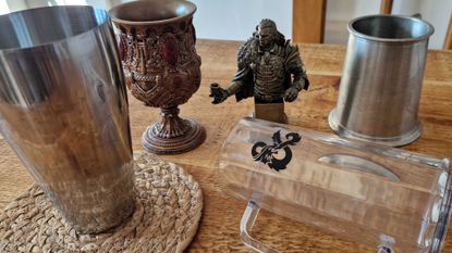 An array of glasses, goblets, mixers, and a figurine on a wooden table