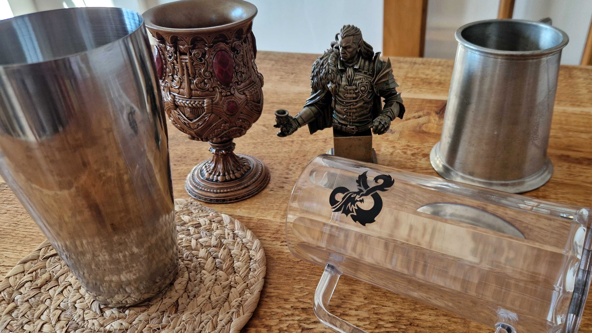 An array of glasses, goblets, mixers, and a figurine on a wooden table