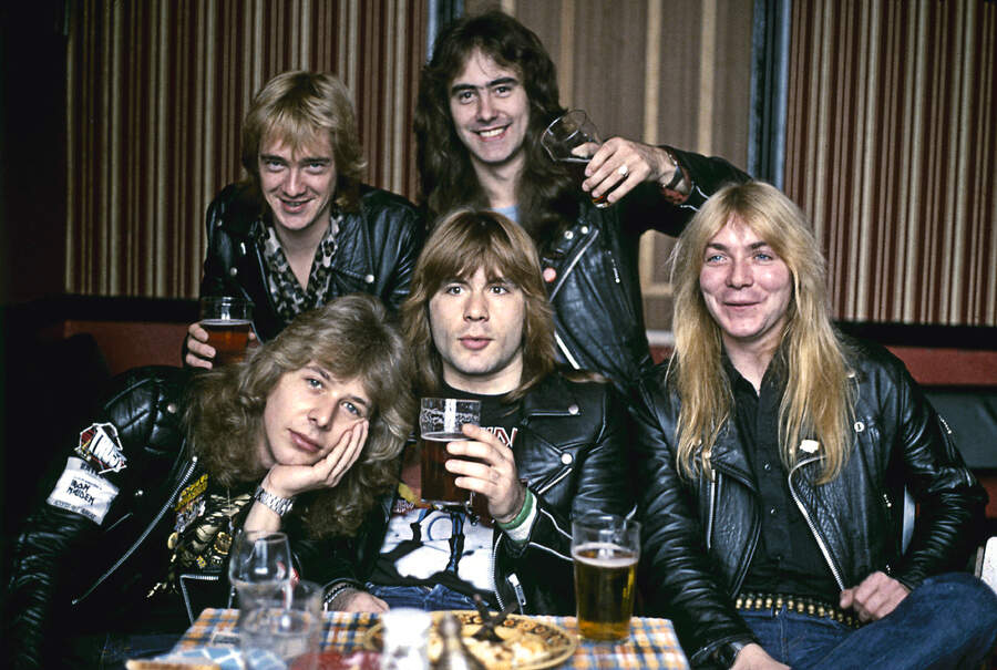 Iron Maiden celebrating with pints of beer in a pub