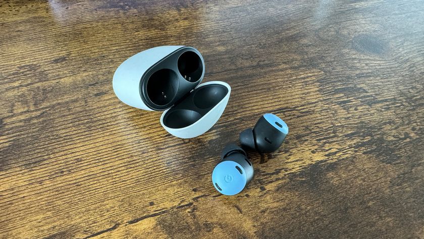 The Google Pixel Buds Pro in-ear headphones with their charging case on a wooden surface.