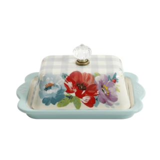 A butter dish with a flower design on it and a blue tray underneath it