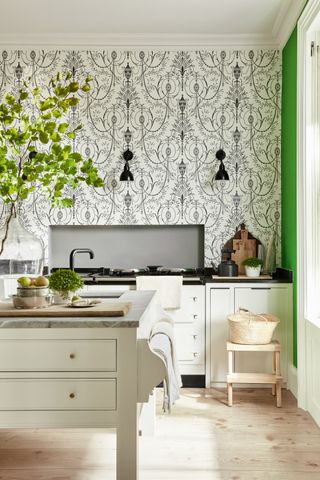 Patterned wallpaper in white kitchen by Little Greene with wooden flooring and foot stool