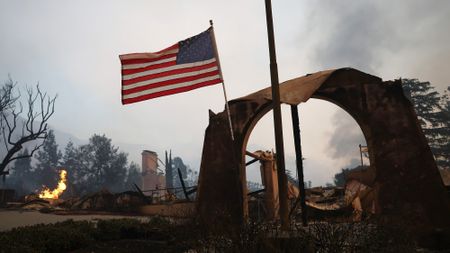 An American flag flies amid burned structures at the Altadena Town & Country Club during the Eaton Fire on January 8, 2025 in Altadena, California