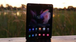 Samsung Galaxy Z Fold 3 on a board with the sun setting behind it