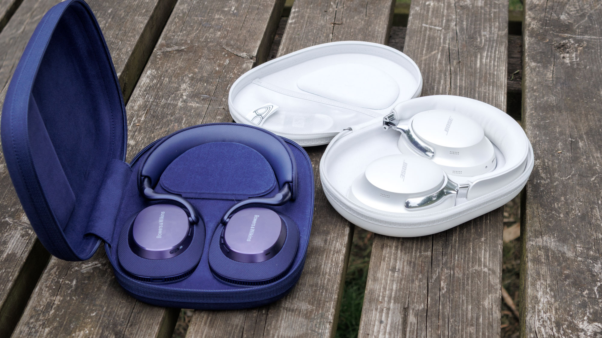 Bowers & Wilkins Px7 S3 vs Bose QuietComfort Ultra Headphones on a wooden surface in their cases