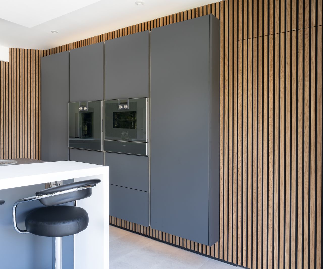 kitchen with wall panelled wall and grey units with built in appliances in centre