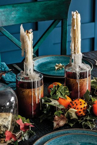 Festive table decorations with melted wax on dripping candlesticks and oranges studded with cloves