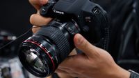 A customer tries out a Canon Inc. EOS Kiss X7i digital single lens reflex (DSLR) camera mounted with an EF 135mm F2L USM lens at an electronics store in Tokyo, Japan, on Wednesday, Oct. 23, 2013