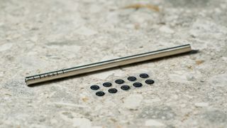 a photograph of a cleaning stick for black earbuds by final with a long, angular stem and black casing, silicone ear tips, and a black oval case reading 'final' with three decorative hexagons