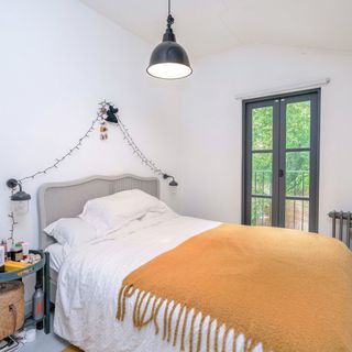 bedroom with with wall grey bed with cushion black door and lamp