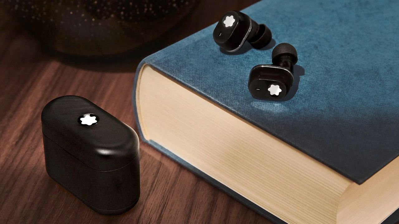 Montblanc MTB 03 headphones on top of a book, charging case on the desk