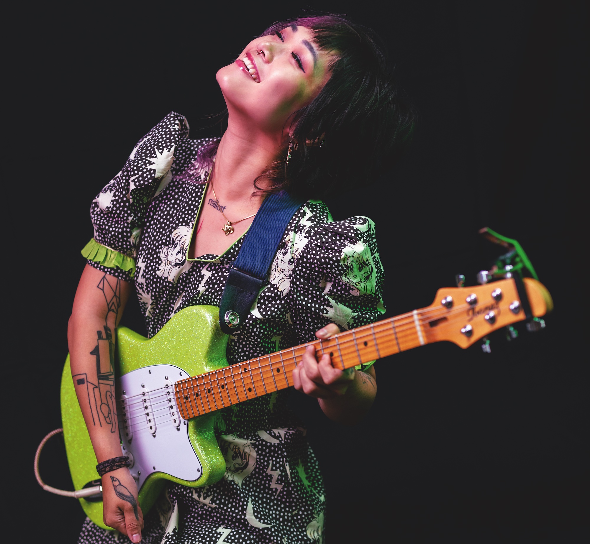 Yvette Young, pictured standing with one of her Ibanez signature guitars