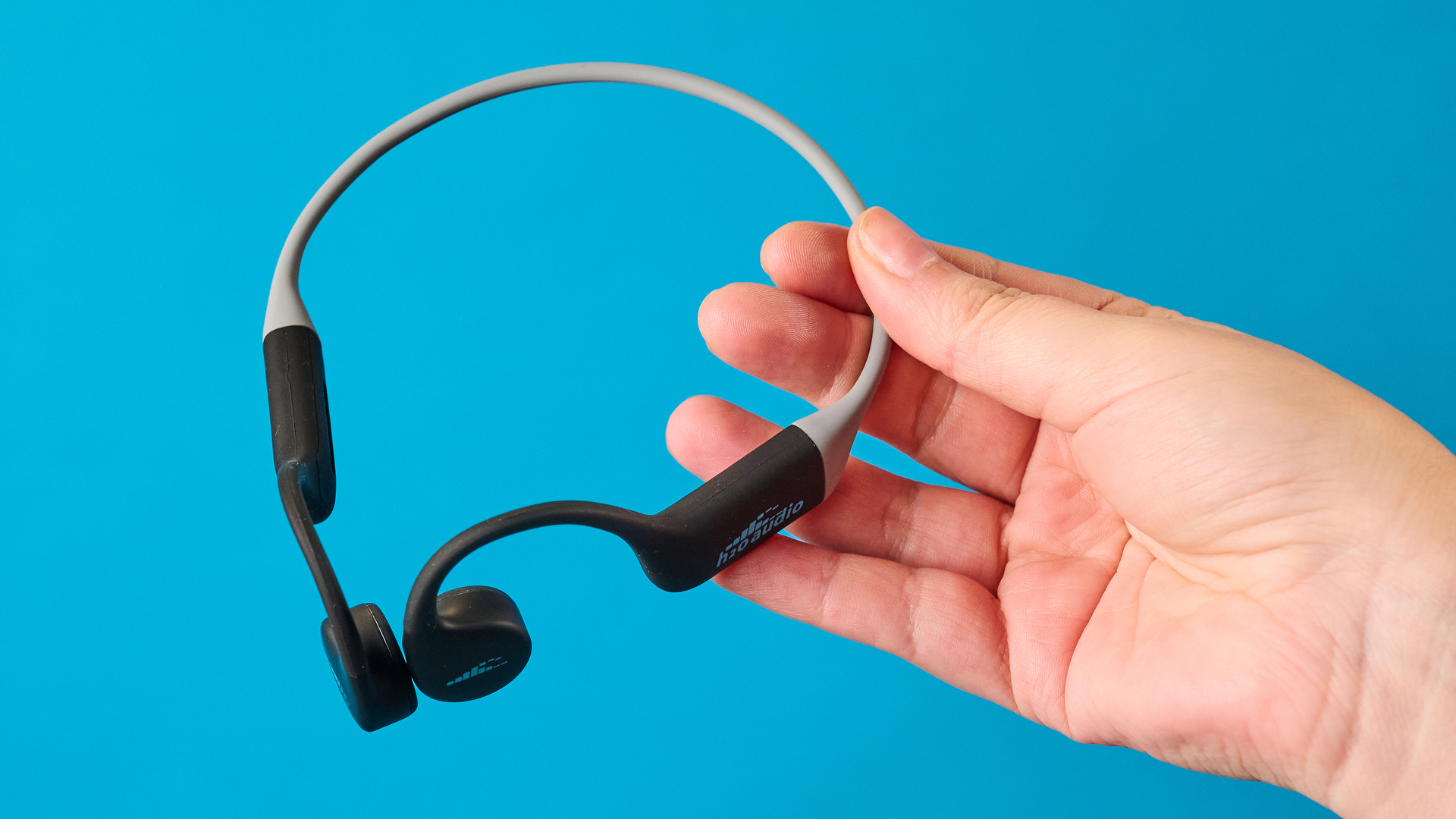 the h2o audio tri run bone conduction headphones photographed against a tom's guide blue background