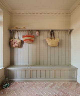 mudroom with shiplap, bench seating herringbone tile layout, hooks, baskets, shelf, cream walls