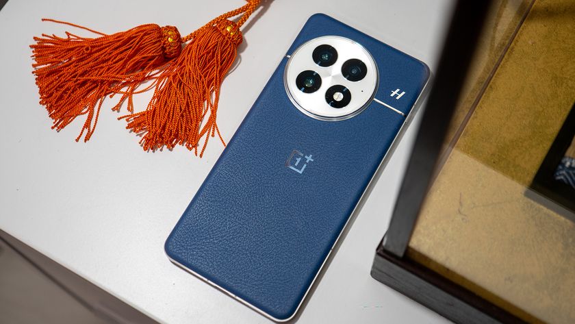 The back of the blue OnePlus 13 next to some orange tassels