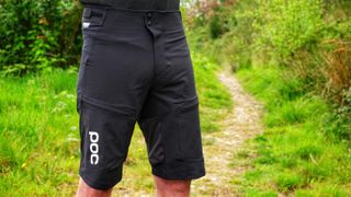 A model wearing POC Resistance shorts by a trail